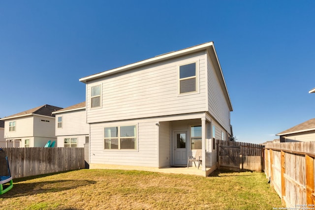 rear view of house with a yard and a trampoline