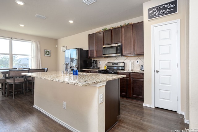 kitchen with a center island with sink, dark brown cabinetry, and stainless steel appliances