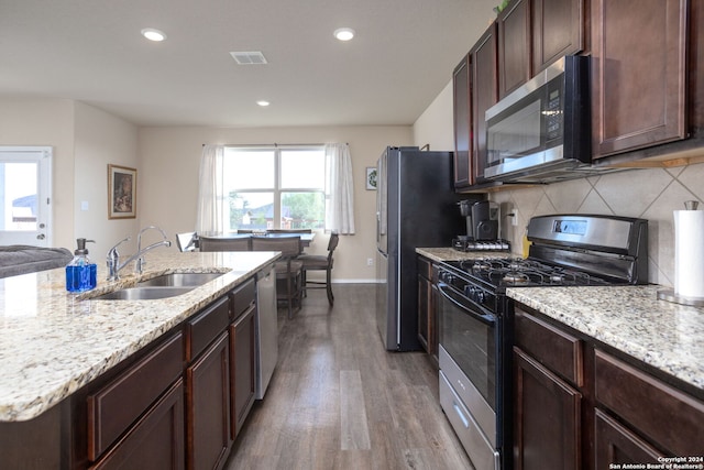 kitchen featuring sink, light stone countertops, tasteful backsplash, light hardwood / wood-style floors, and stainless steel appliances