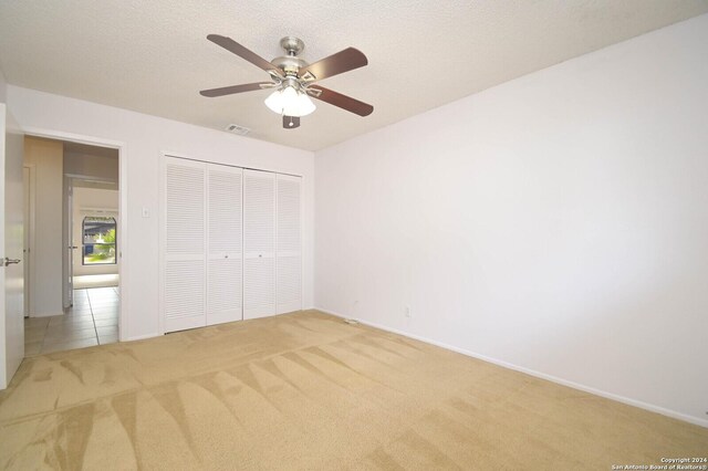 unfurnished bedroom with ceiling fan, light colored carpet, and a closet