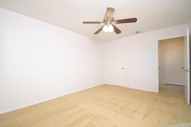 carpeted spare room featuring a textured ceiling and ceiling fan