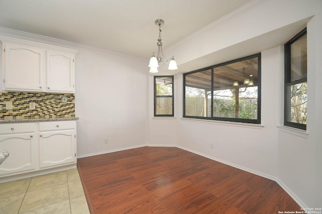 unfurnished dining area with light tile patterned floors, ornamental molding, and a chandelier