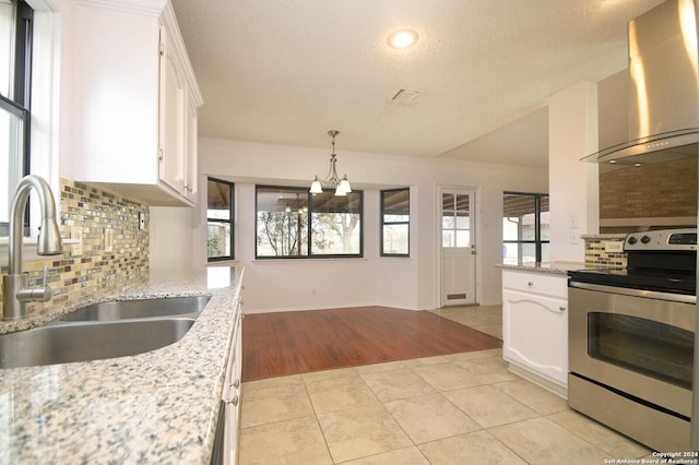 kitchen featuring wall chimney exhaust hood, sink, white cabinetry, and stainless steel range with electric cooktop