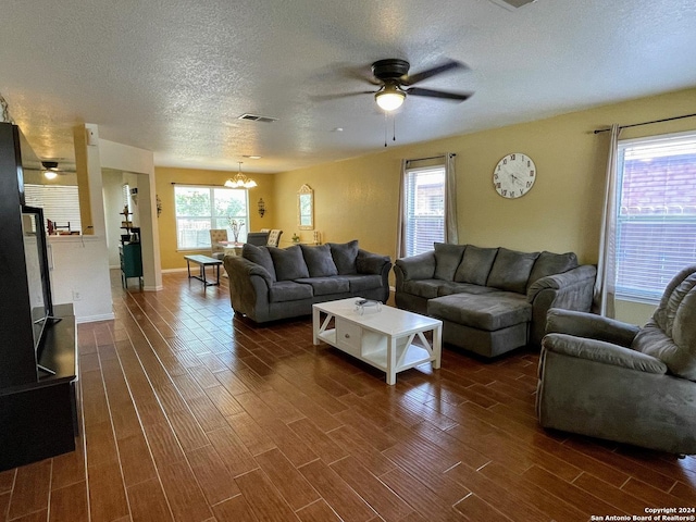 living room featuring a textured ceiling and ceiling fan with notable chandelier