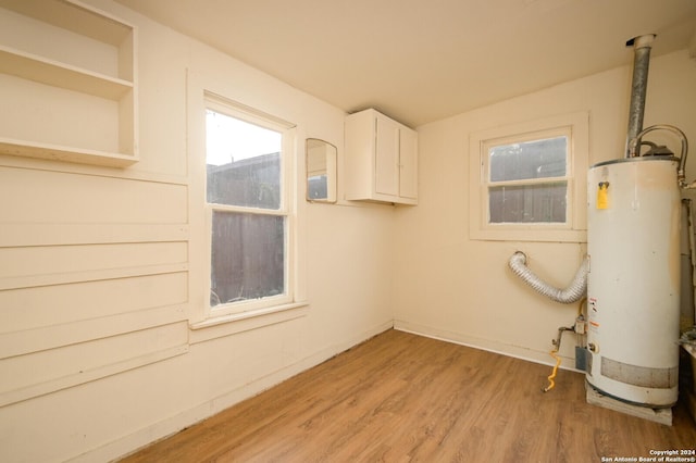 laundry area featuring light hardwood / wood-style floors, cabinets, and water heater