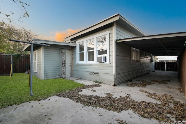 view of front facade with a carport, cooling unit, and a lawn