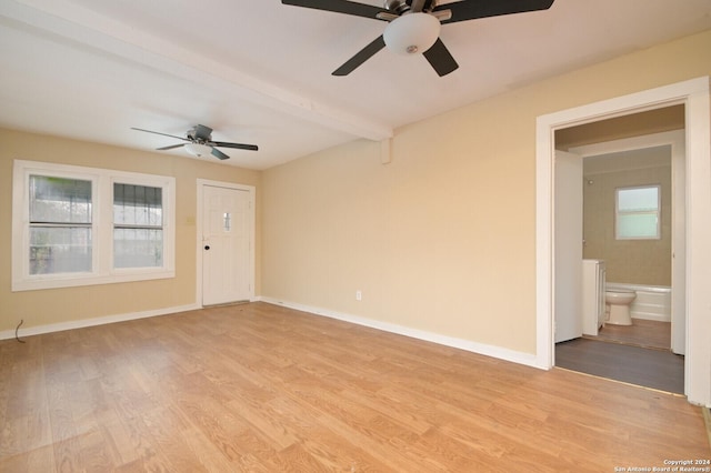 empty room with beamed ceiling, light hardwood / wood-style floors, and ceiling fan