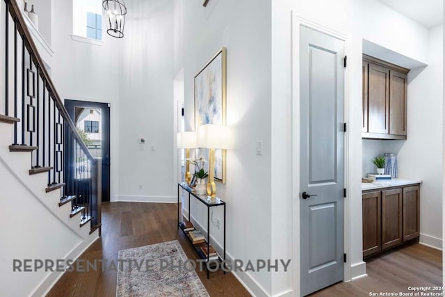 foyer with a towering ceiling, dark wood-type flooring, and an inviting chandelier