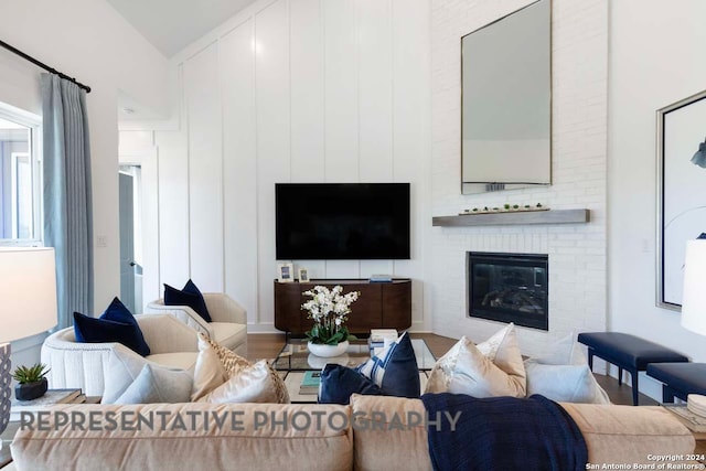 living room with wood-type flooring, lofted ceiling, and a brick fireplace