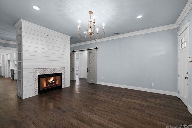 653 Center Grn, New Braunfels, TX 78130 - unfurnished living room featuring dark wood-type flooring, crown molding, a tile fireplace, a barn door, and an inviting chandelier