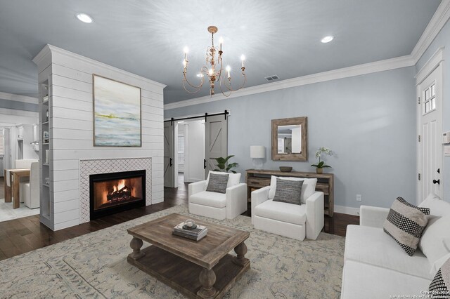 653 Center Grn, New Braunfels, TX 78130 - living room featuring ornamental molding, a barn door, a notable chandelier, hardwood / wood-style floors, and a tiled fireplace