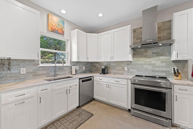 kitchen featuring white cabinets, wall chimney range hood, sink, appliances with stainless steel finishes, and tasteful backsplash