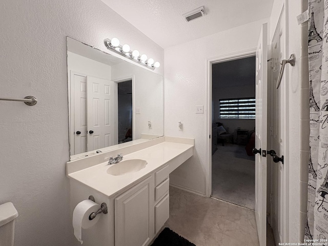 bathroom with vanity, toilet, and a textured ceiling