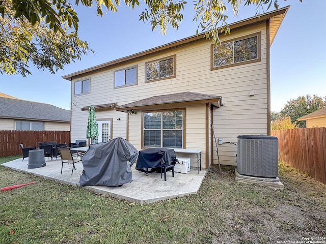 rear view of property with a lawn, central air condition unit, and a patio