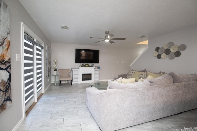 living room featuring ceiling fan and a textured ceiling