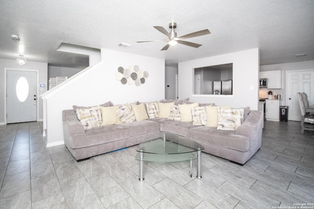 living room with ceiling fan and a textured ceiling