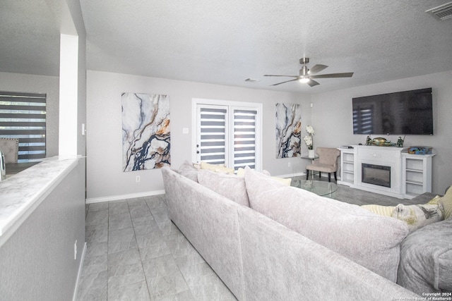 living room featuring ceiling fan and a textured ceiling