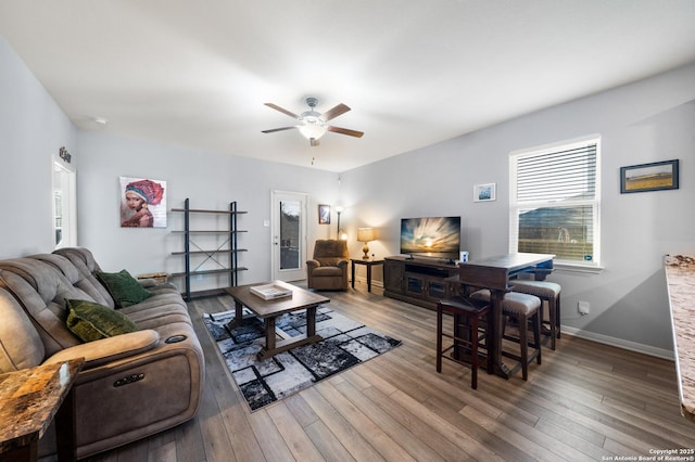 living room featuring a ceiling fan, baseboards, and wood finished floors