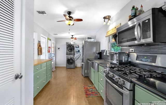 kitchen with stacked washer and clothes dryer, sink, light hardwood / wood-style flooring, ceiling fan, and appliances with stainless steel finishes