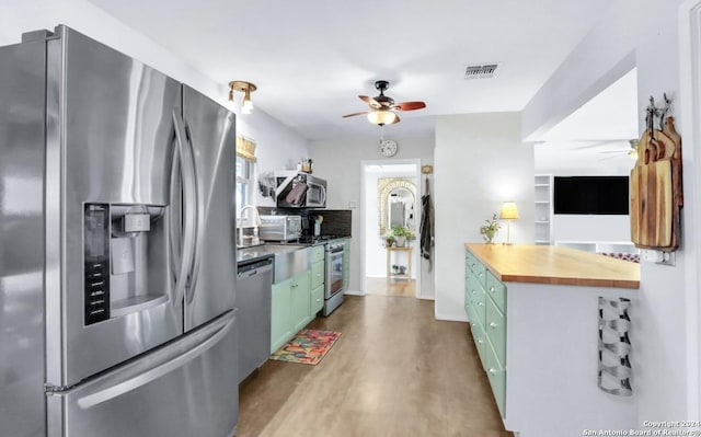 kitchen featuring green cabinets, ceiling fan, appliances with stainless steel finishes, butcher block countertops, and wood-type flooring