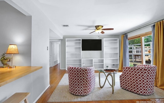 living room featuring hardwood / wood-style floors, ceiling fan, and built in shelves