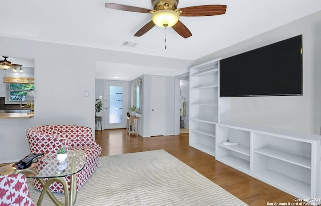 living room featuring hardwood / wood-style flooring, ceiling fan, and sink