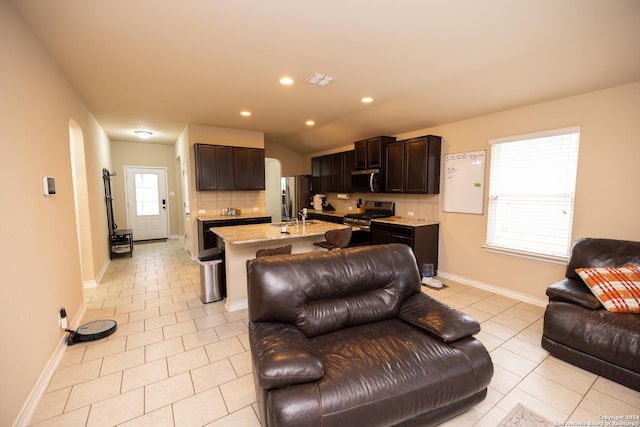 tiled living room with vaulted ceiling, a healthy amount of sunlight, and sink