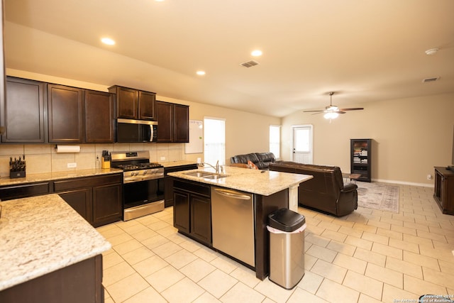 kitchen with dark brown cabinetry, stainless steel appliances, ceiling fan, sink, and an island with sink