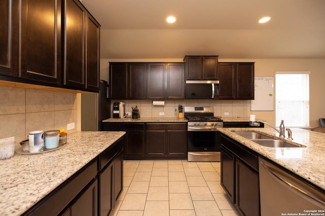 kitchen with sink, backsplash, dark brown cabinets, light tile patterned floors, and appliances with stainless steel finishes