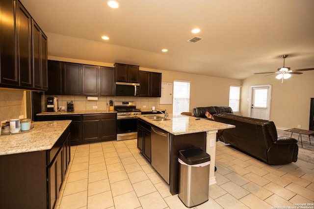 kitchen featuring ceiling fan, tasteful backsplash, a center island with sink, dark brown cabinets, and appliances with stainless steel finishes