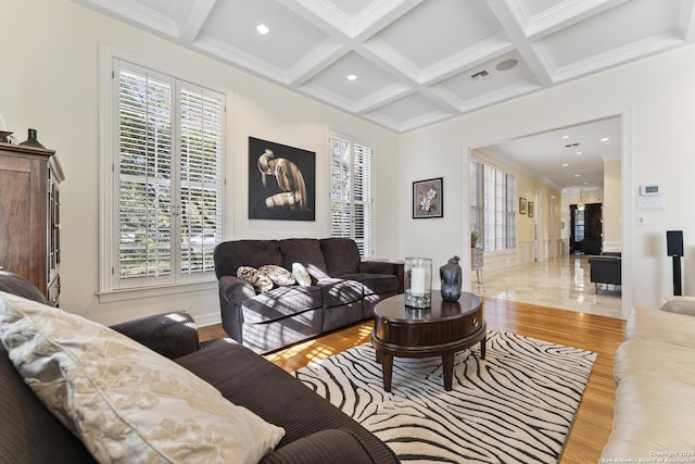 living room featuring beam ceiling, ornamental molding, light hardwood / wood-style flooring, and coffered ceiling