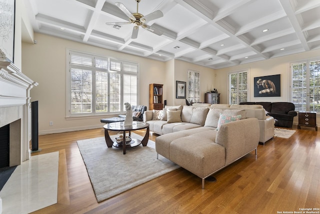 living room with a fireplace, light wood-type flooring, plenty of natural light, and beamed ceiling