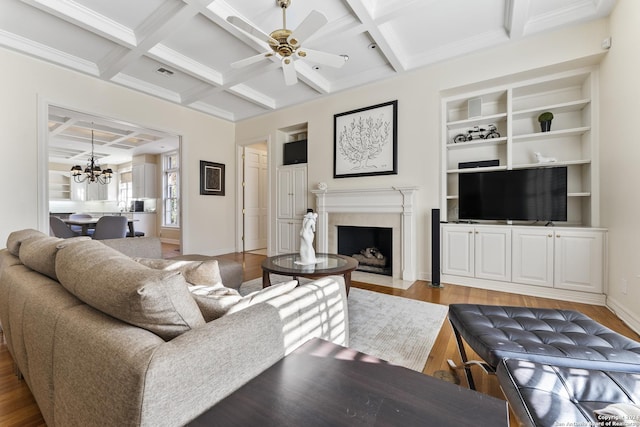 living room featuring beamed ceiling, ceiling fan with notable chandelier, and coffered ceiling