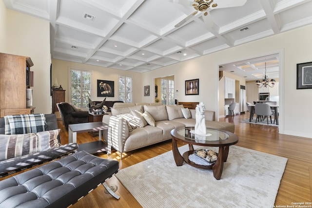 living room with beam ceiling, ceiling fan with notable chandelier, hardwood / wood-style flooring, and coffered ceiling