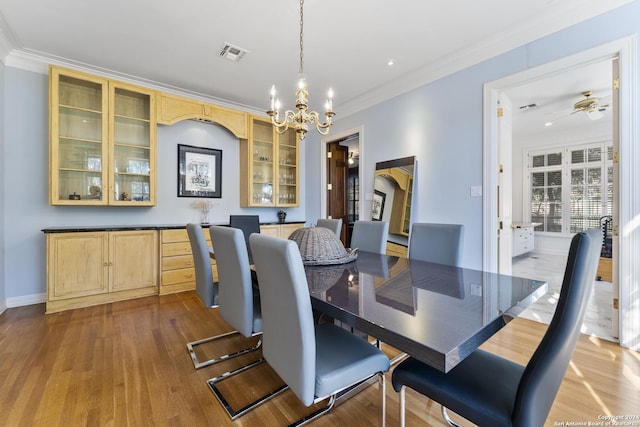 dining room featuring light wood-type flooring, ceiling fan with notable chandelier, and ornamental molding