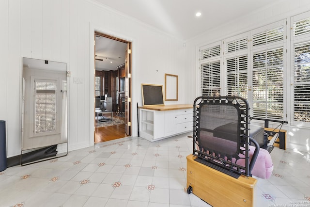 interior space with wood walls, light tile patterned flooring, and ornamental molding