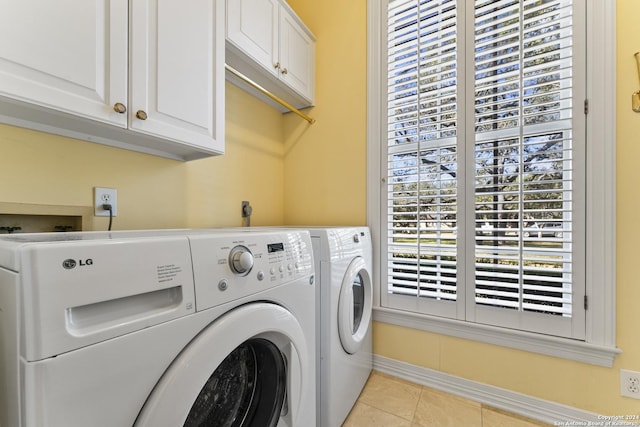 clothes washing area with cabinets, independent washer and dryer, and light tile patterned floors