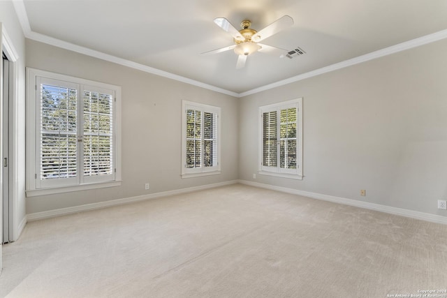 carpeted spare room with plenty of natural light, crown molding, and ceiling fan