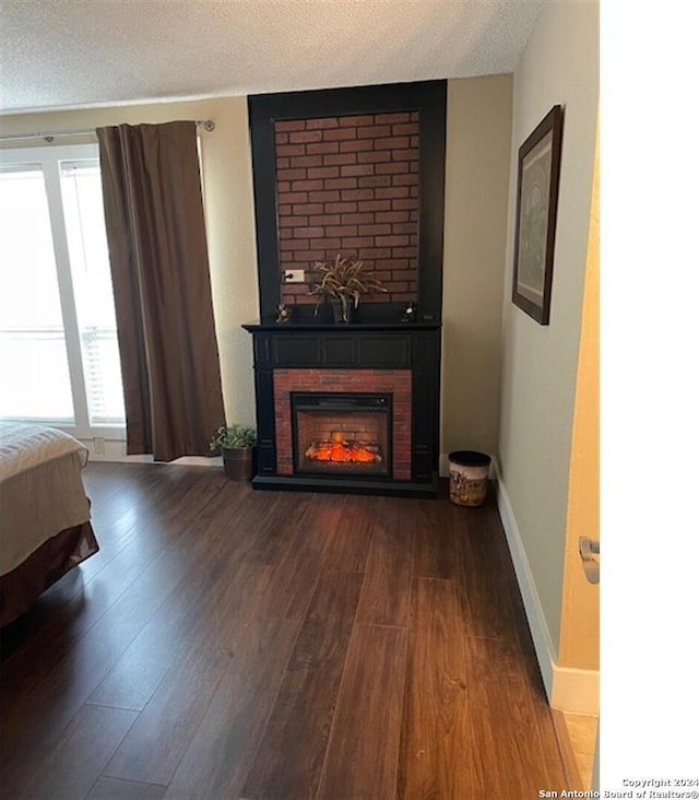 unfurnished bedroom with a textured ceiling, a large fireplace, and wood-type flooring