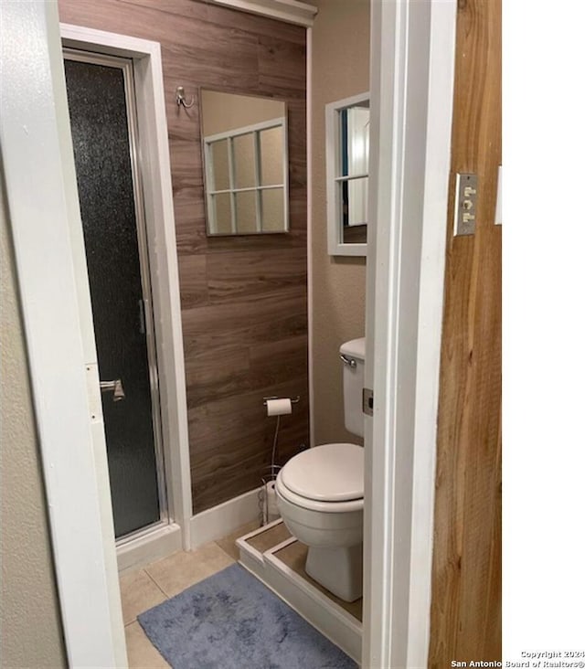 bathroom featuring tile patterned flooring, toilet, and wooden walls