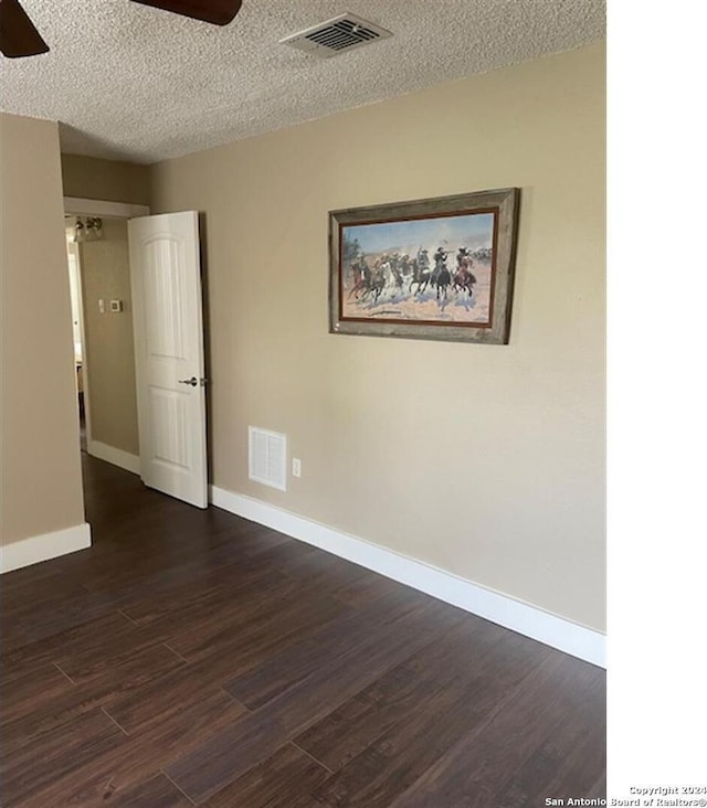 empty room featuring ceiling fan, dark hardwood / wood-style flooring, and a textured ceiling