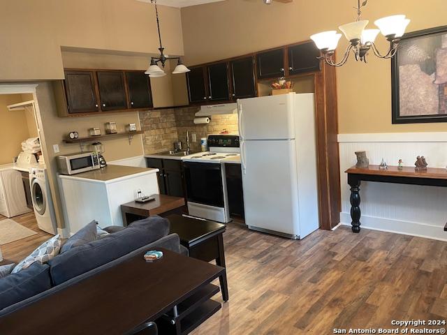 kitchen with washer / dryer, white appliances, hanging light fixtures, and an inviting chandelier