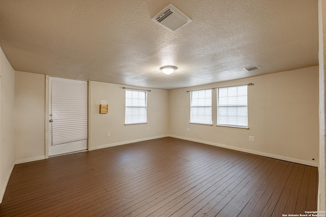 empty room featuring a textured ceiling and dark hardwood / wood-style floors