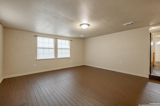 spare room featuring a textured ceiling and dark hardwood / wood-style flooring