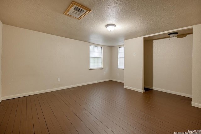 unfurnished room featuring dark hardwood / wood-style flooring and a textured ceiling