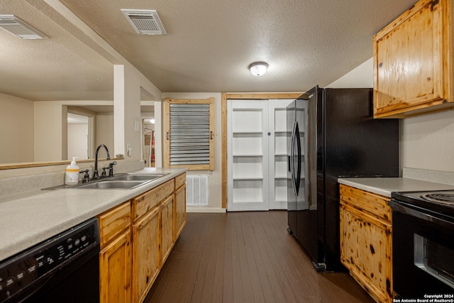 kitchen featuring dark hardwood / wood-style flooring, sink, black appliances, and a textured ceiling