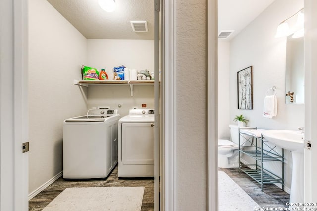 laundry area featuring a textured ceiling, washing machine and dryer, and dark wood-type flooring