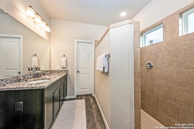 bathroom featuring vanity, wood-type flooring, and tiled shower