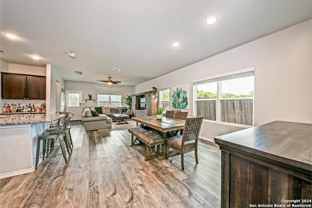 dining space with bar area, ceiling fan, a textured ceiling, and light hardwood / wood-style flooring