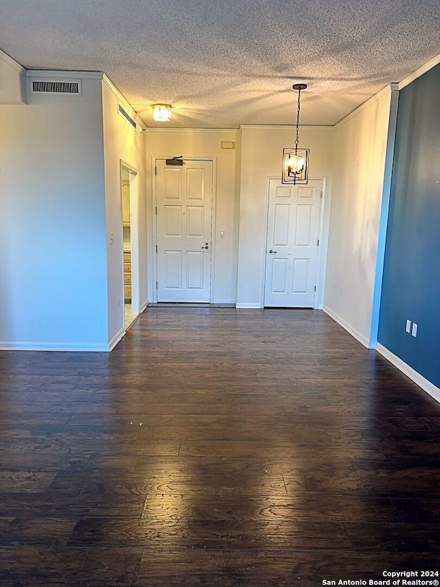 empty room with dark wood-type flooring, a textured ceiling, and an inviting chandelier